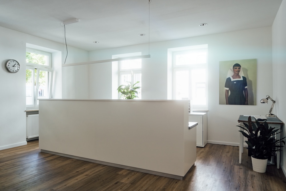 Empfangsbereich mit Holzboden und Wandbild – Hausarzt München