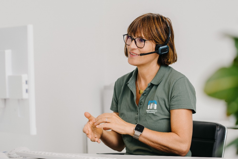 Hausarzt Schwabing – Dr. Mutschler – Telefonische Krankschreibung Mitarbeiterin mit Headset am Telefon – telefonische Krankschreibung beim Hausarzt München